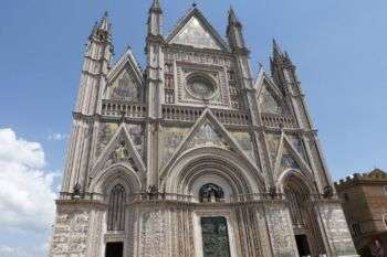 奥维多大教堂外立面:一个巨大的、华丽的灰色石头结构，有各种拱门和三角形的点。